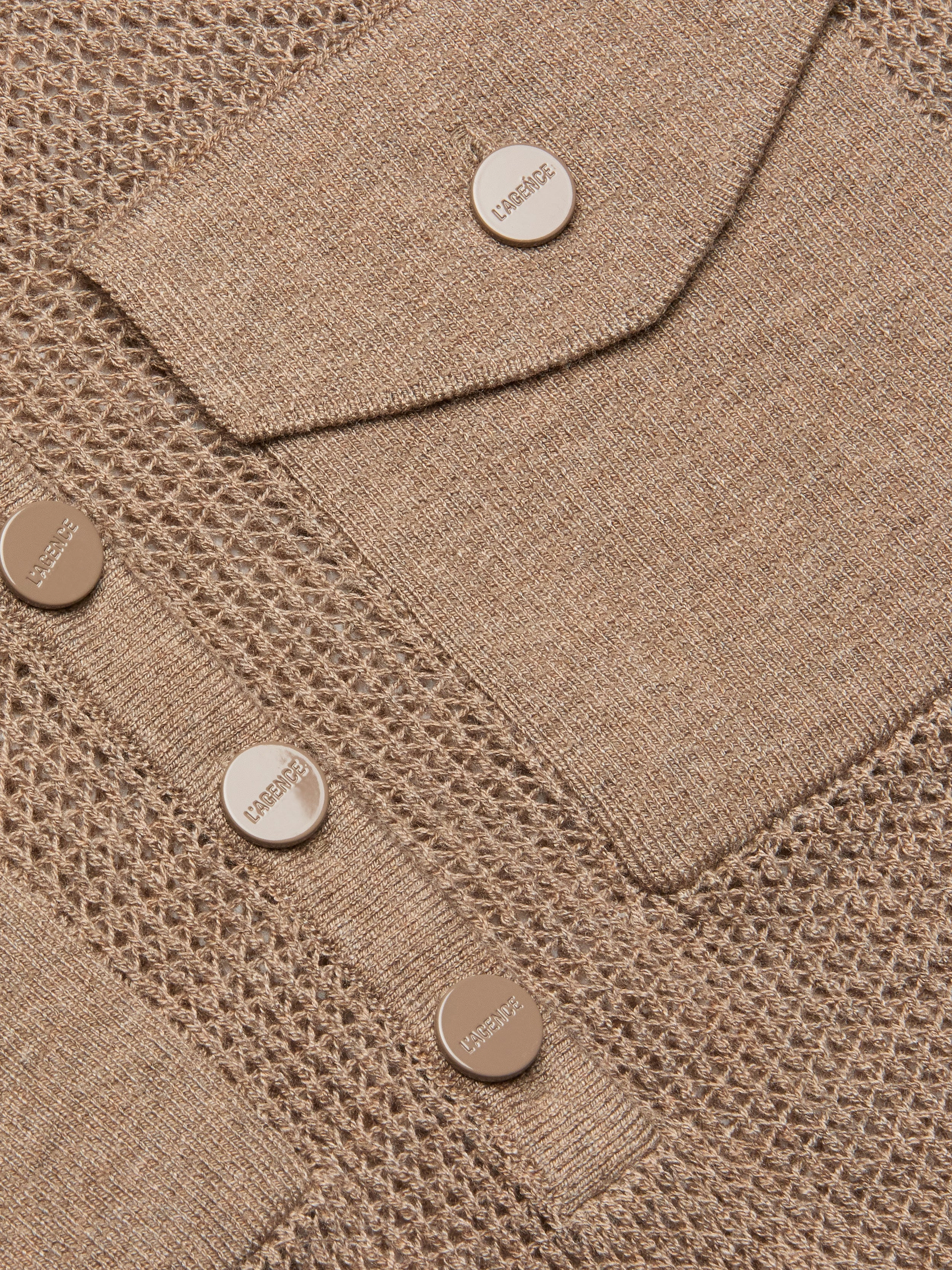Close-up of the Carine Top in beige lightweight knit fabric with mesh and solid patterns, featuring metallic buttons embossed with LABISSE and a utility pocket flap.