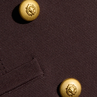 Close-up of the Amelia Knit Blazer in dark brown, featuring soft tailoring, textured knit fabric, two shiny gold buttons with a raised floral design, and a partial glimpse of the pocket seam.