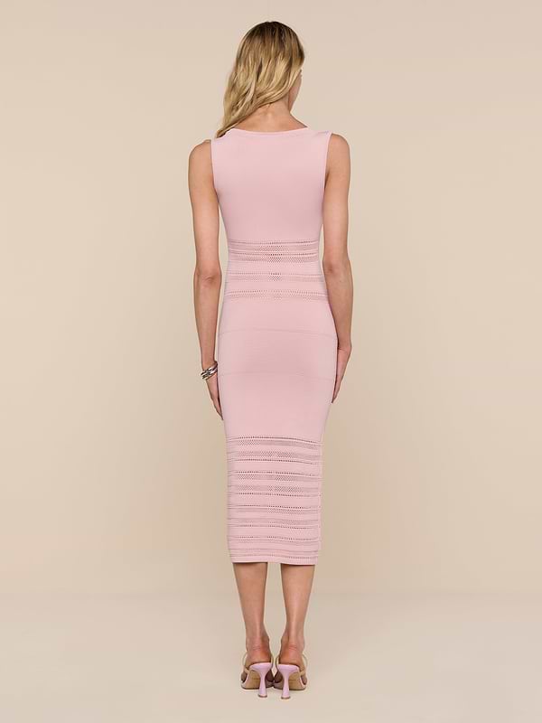 A woman with long blonde hair stands facing away, wearing the sleeveless, fitted Taren Knit Dress in light pink and pink high-heeled sandals against a plain white background.