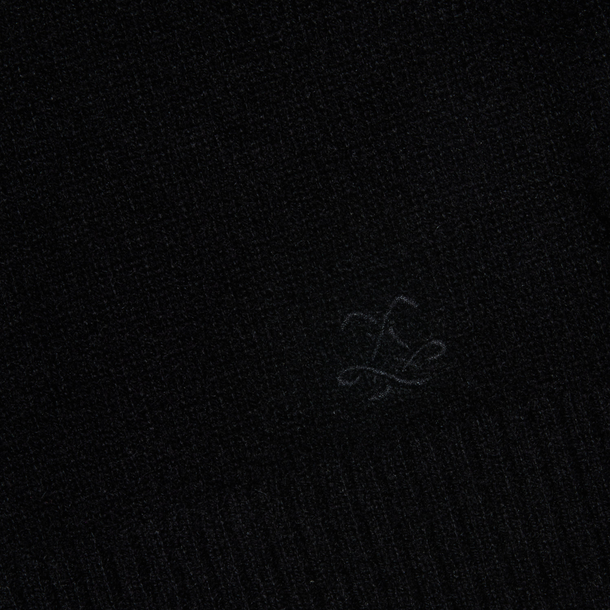 A close-up of the Filou Cashmere Tank in black, showcasing its textured fabric and a subtle embroidered design with flowing, intersecting lines near the center—an ideal detail for luxury layering or building your sweater capsule.