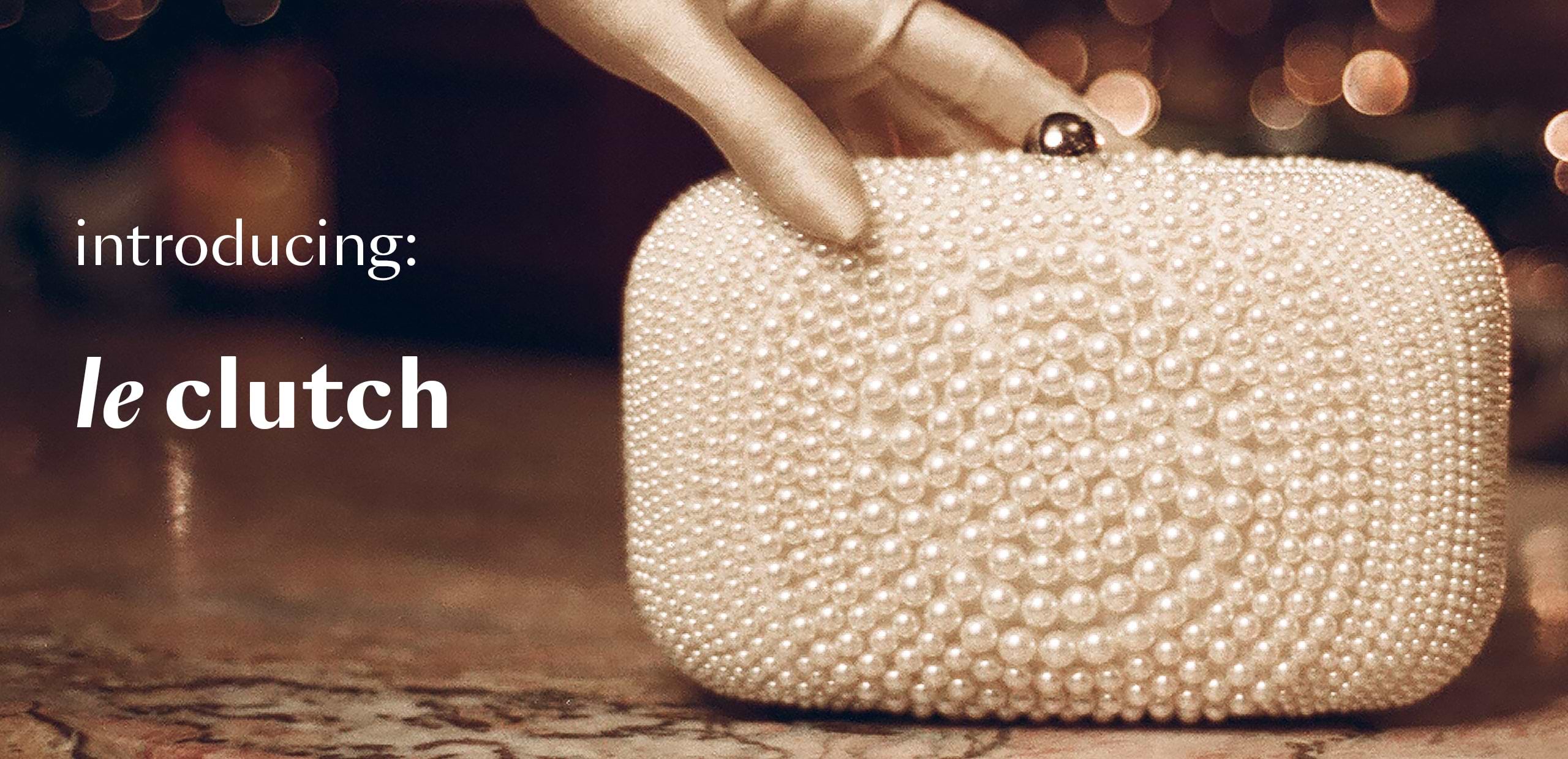 Pearl clutch being held with text 'introducing: le clutch' on a blurred background