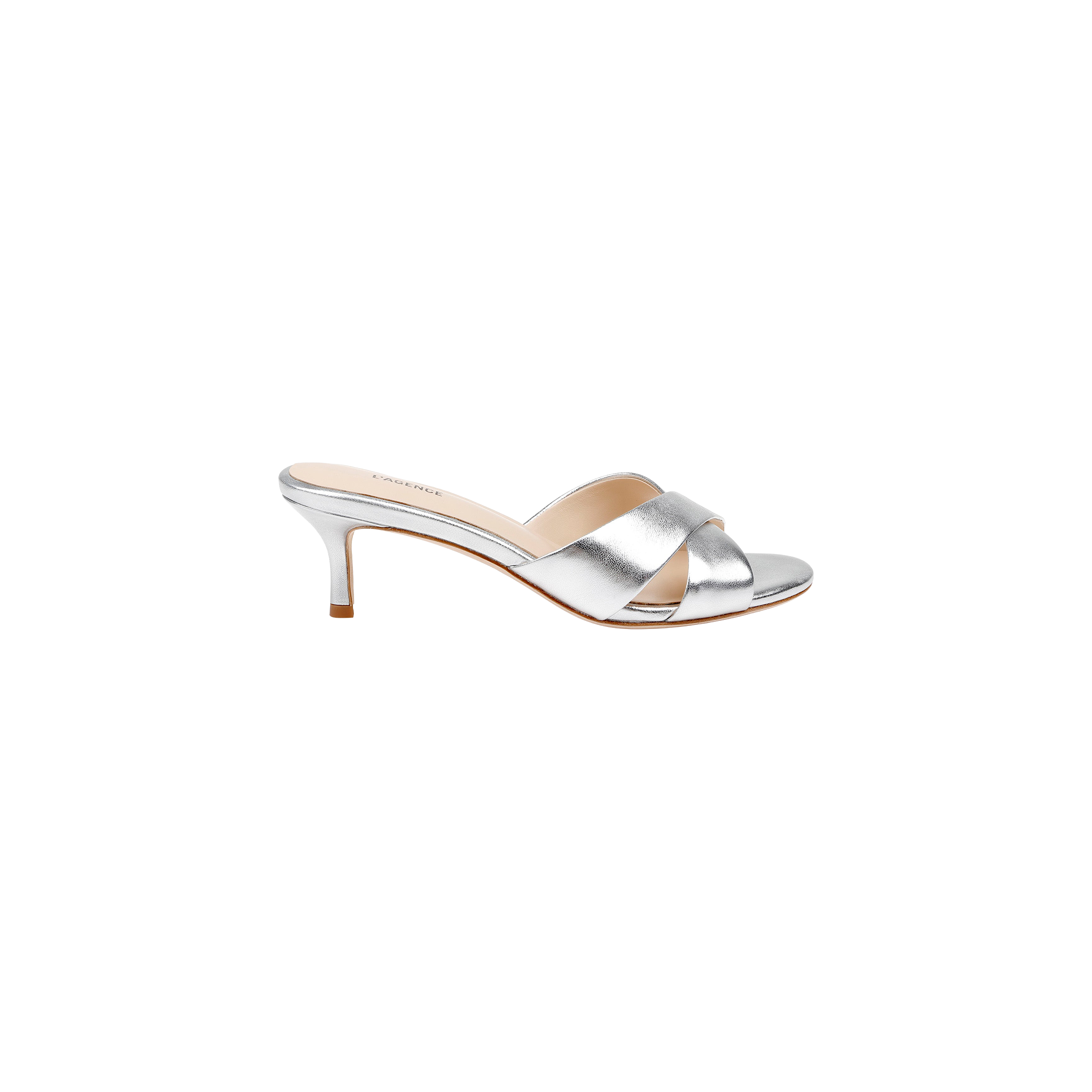 The Aveline Kitten-Heel Sandal is a silver mule crafted from metallic leather, featuring crisscross straps and a strappy vamp with an open toe, shown in a side view against a white background.