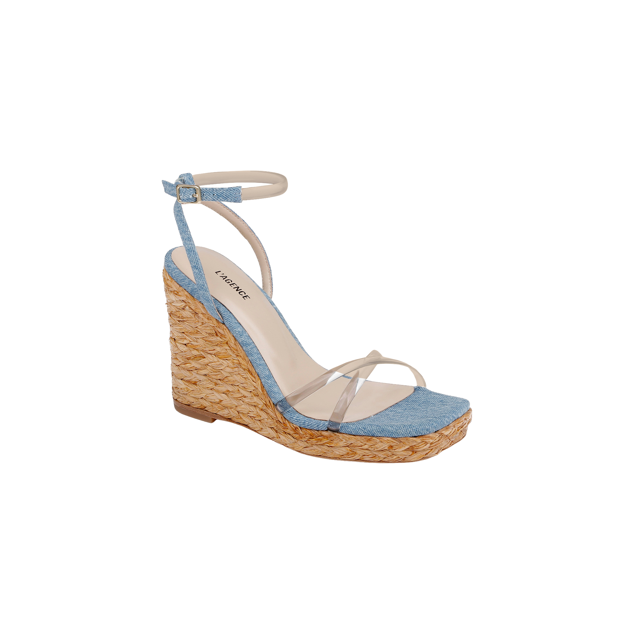 The Malone Wedge Espadrille is a bohemian-style wedge sandal showcasing a woven raffia heel, light blue fabric across the toe, clear straps over the foot, and a light ankle strap with buckle closure. Its cushioned beige insole provides comfort and is finished with a brand label.