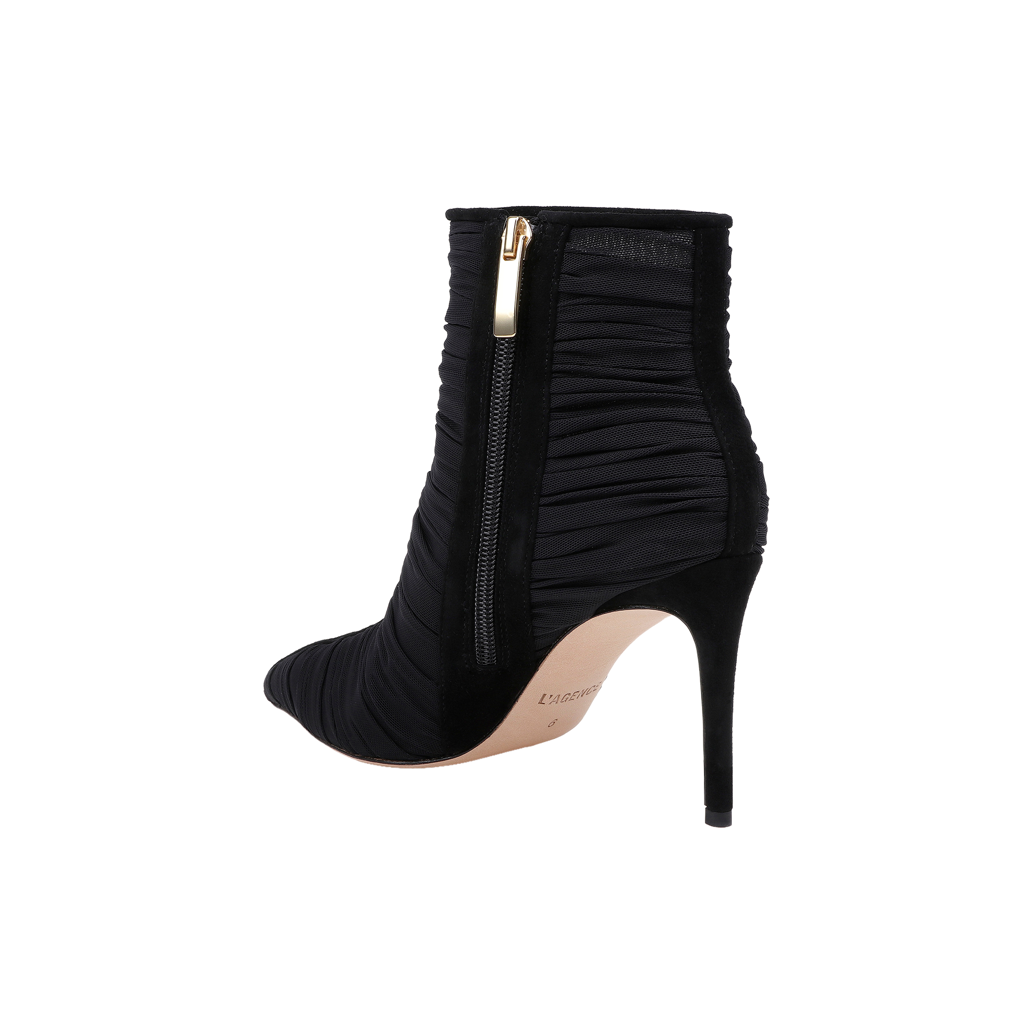 The Fulton Mesh Bootie is a black stiletto bootie featuring ruched mesh fabric, a pointed toe, and a gold side zipper. This heeled bootie showcases a slim stiletto heel and a light-colored sole.
