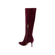 The Herald Boot is a single knee-high, burgundy suede boot featuring a pointed toe, high stiletto heel, and a convenient side zipper—an elegant choice for chic autumn style—shown against a white background.