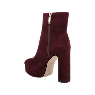The Soho Bootie, shown on a white background, features burgundy suede, a platform sole, chunky block heel, gold zipper detail, and a light-colored sole.