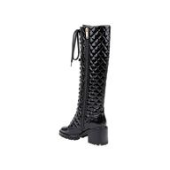 Introducing the Tribeca Boot: This black, knee-high combat boot features glossy patent leather with a diamond-patterned quilted texture. Designed with a chunky block heel, a lace-up front, and a convenient side zipper, the Tribeca Boot is finished with a lugged sole for superior grip.