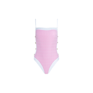 The Tory Bandeau One-Piece Swimsuit is a pink one-piece featuring thin white shoulder straps and white trim. Metallic button details decorate the sides, while textured bouclé fabric adds interest throughout. The swimsuit is photographed against a plain white background.
