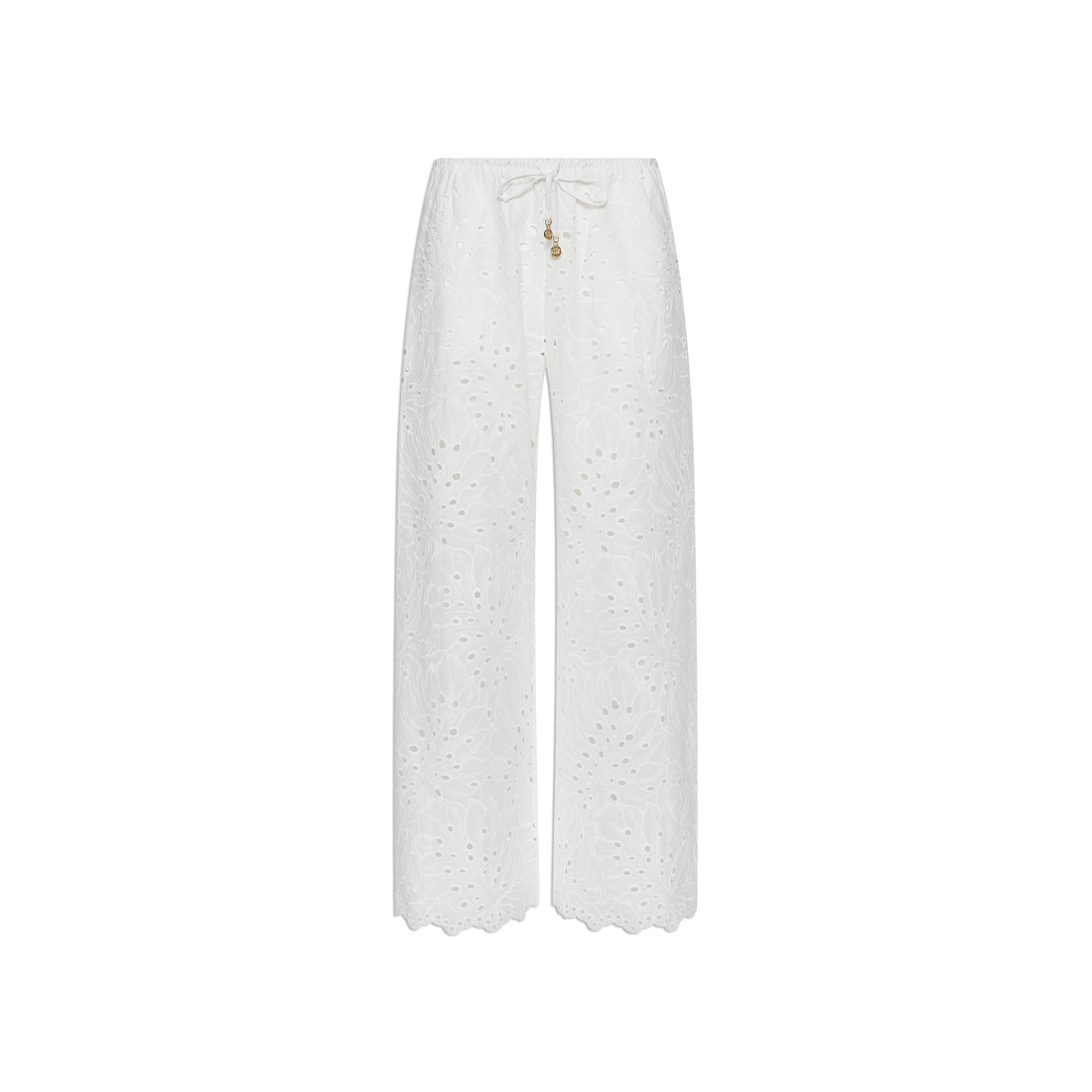 The Geraldine Eyelet Cover-Up Pant features a white, wide-leg silhouette crafted from cotton eyelet, complete with scalloped hems and a tie waist accented by small decorative charms—making it perfect for resort wear. Shown against a plain white background.