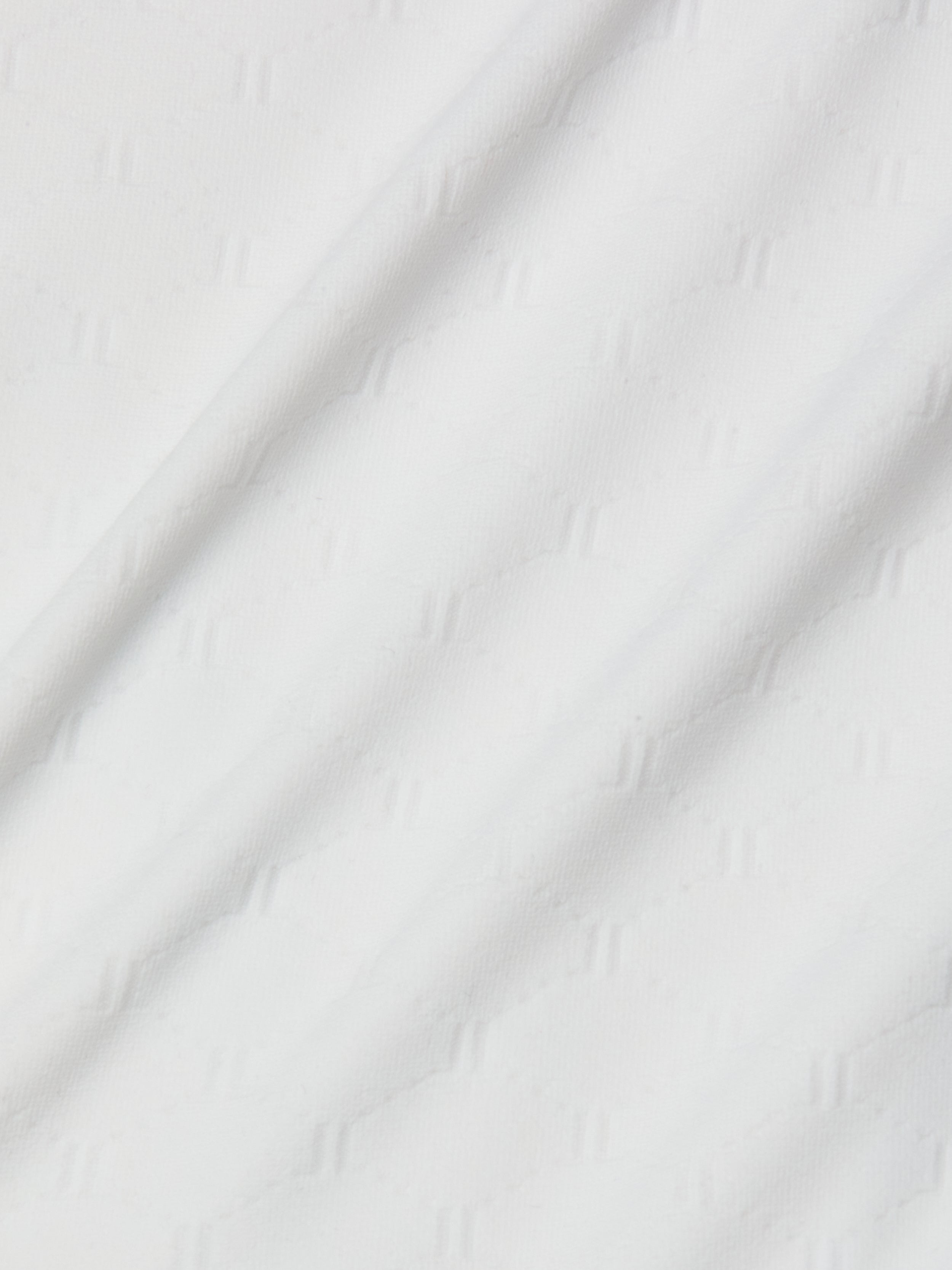 Close-up of the Breana Plunge One-Piece Swimsuit, featuring white fabric with a subtle diagonal textured pattern that creates gentle folds and soft shadows on the surface.