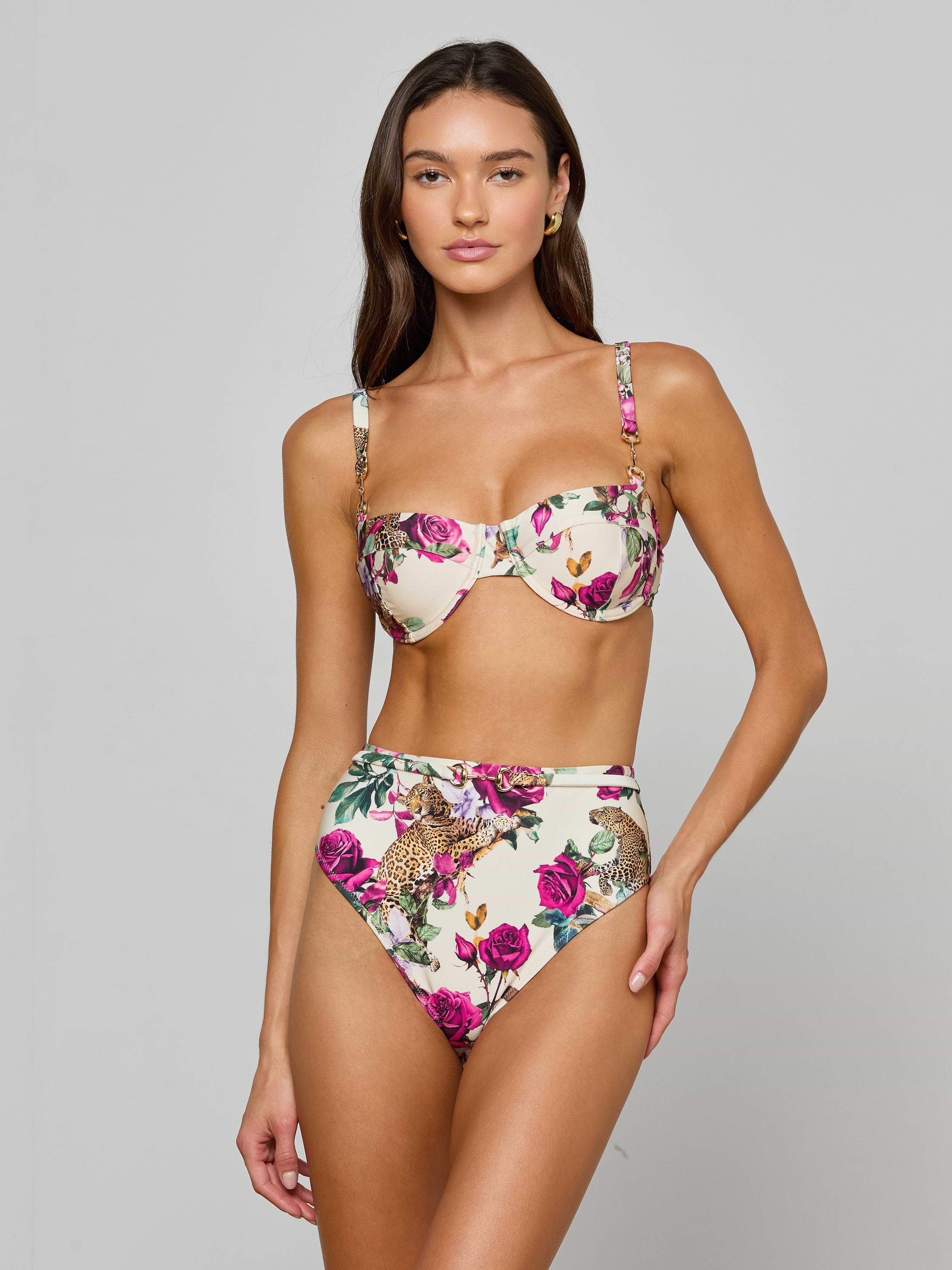 A woman wearing the Alexandria Bikini Top, a high-waisted bikini featuring rose leopard print and pink floral patterns with a balconette design, stands against a plain light background.