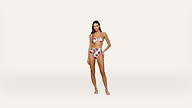 A woman stands on a plain white background wearing a floral bikini with a strapless top and high-waisted bottoms. She has long hair and is posing with one hand on her hip and her legs slightly apart.