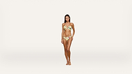 A woman with long dark hair stands barefoot on a white background, wearing a yellow floral bikini. She faces forward with a neutral expression and her arms resting naturally by her sides.