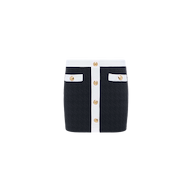 Introducing the Coco Mini Skirt Cover-Up: a black bouclé mini skirt featuring white trim, gold buttons down the front, and two front pockets accented with matching white trim and gold buttons—beautifully displayed on a plain white background.