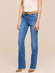 A woman wearing Petite Ruth Straight-Leg Jeans in heritage indigo wash, a tan belt, a sleeveless beige top, and tan high-heeled shoes stands against a plain white background.