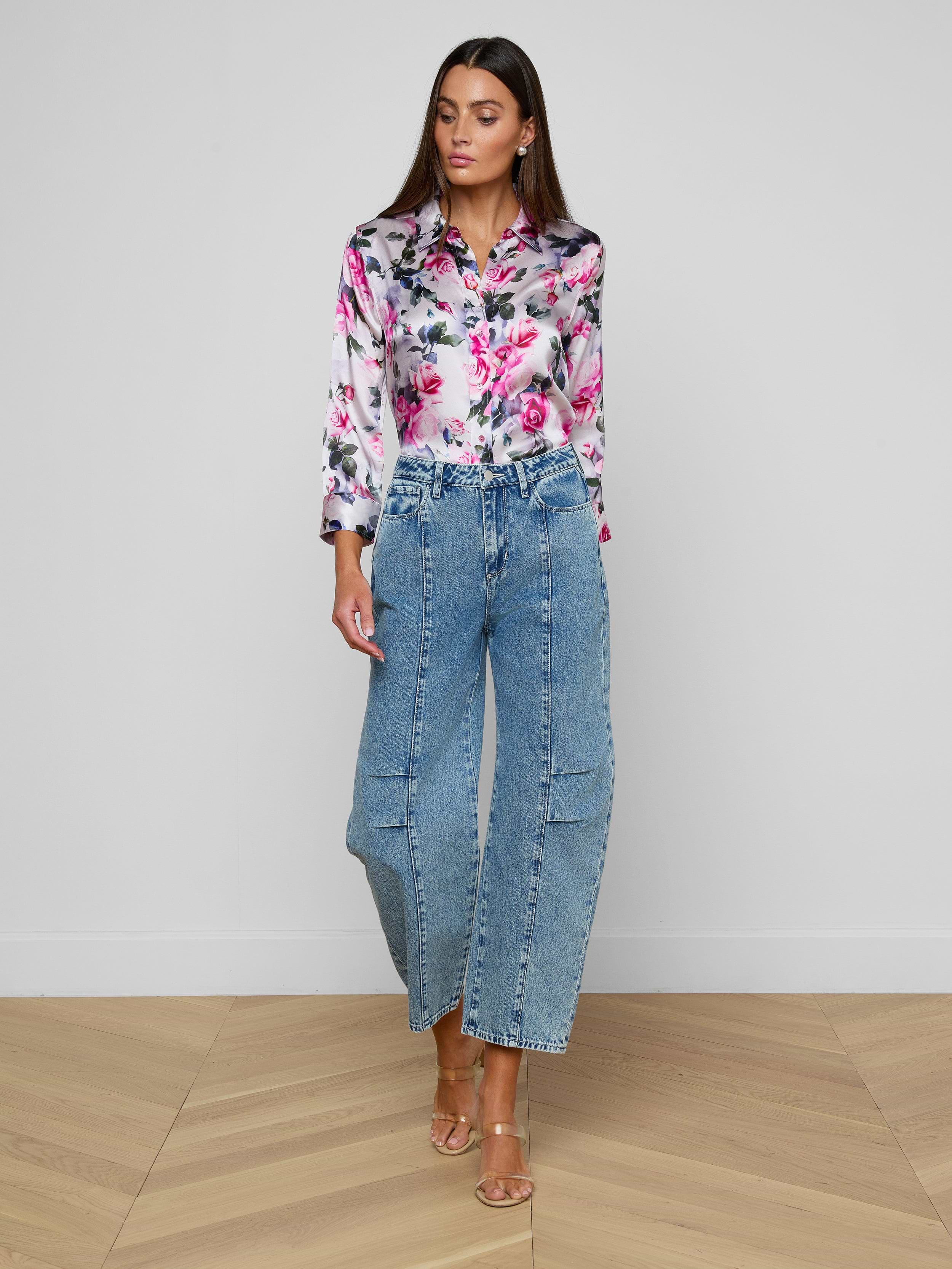 Woman standing against a white background, wearing a floral long-sleeve shirt, the Reba Rodeo Jean—high rise, all-cotton denim with a barrel-leg silhouette—and beige heeled sandals.