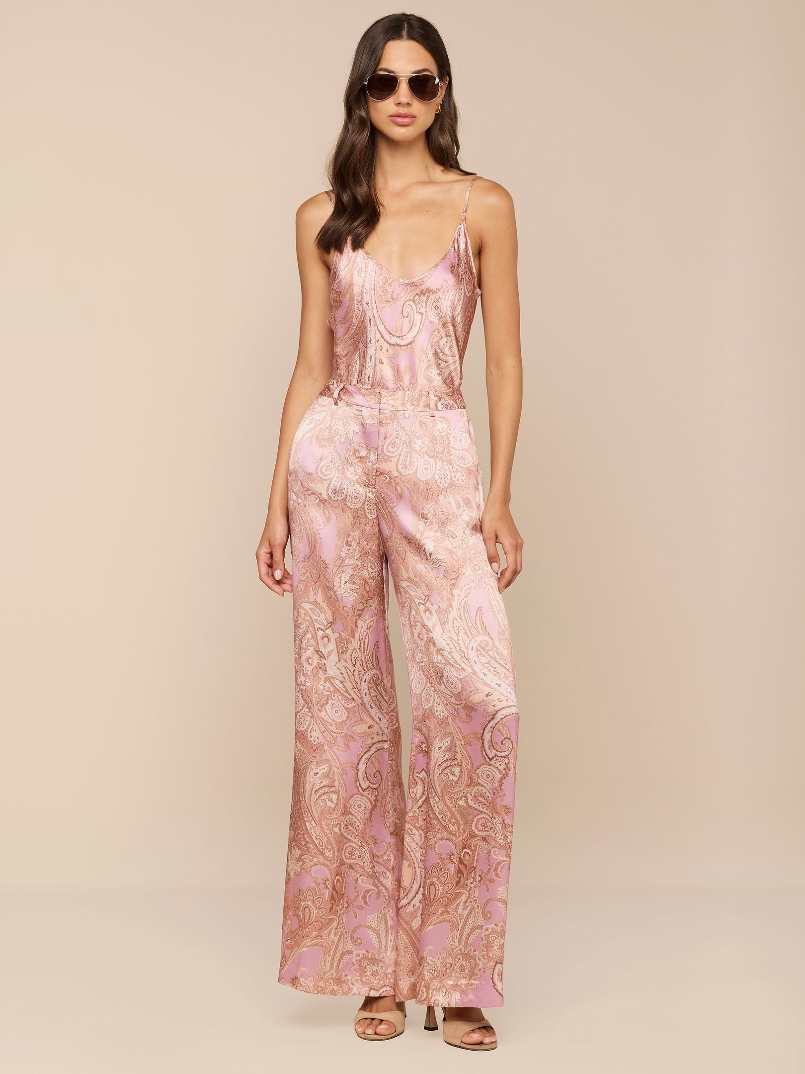 Woman wearing sunglasses and the Pilar Silk Wide-Leg Pant, featuring a mauve paisley print, standing against a plain white background.