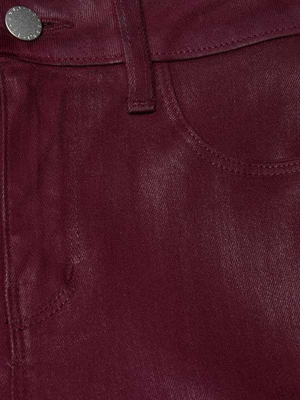 Close-up of the Selma Coated Bootcut Jean in maroon shows a pocket, belt loop, and metallic button. The coated denim’s texture and stitching details are highlighted in this high-rise baby bootcut style.