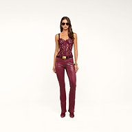 A woman wearing sunglasses, a burgundy lace top, and the Selma Coated Bootcut Jean stands against a plain white background.