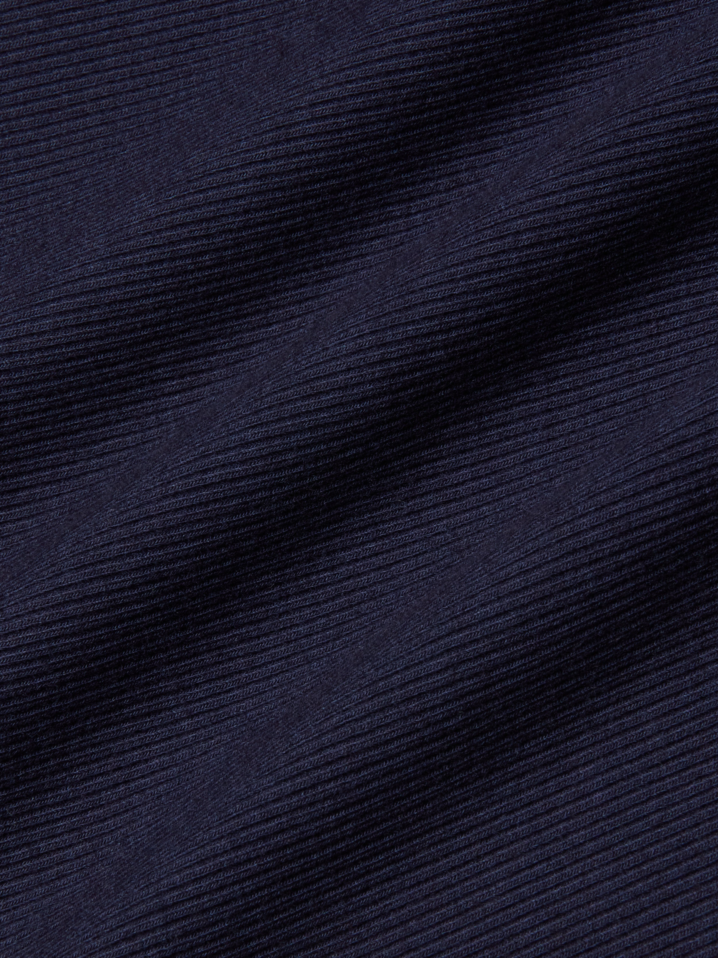 Close-up of the Adira Scoopneck Tank in dark navy blue stretch rib fabric, featuring diagonal textured lines with fine horizontal ridges and subtle light reflections.