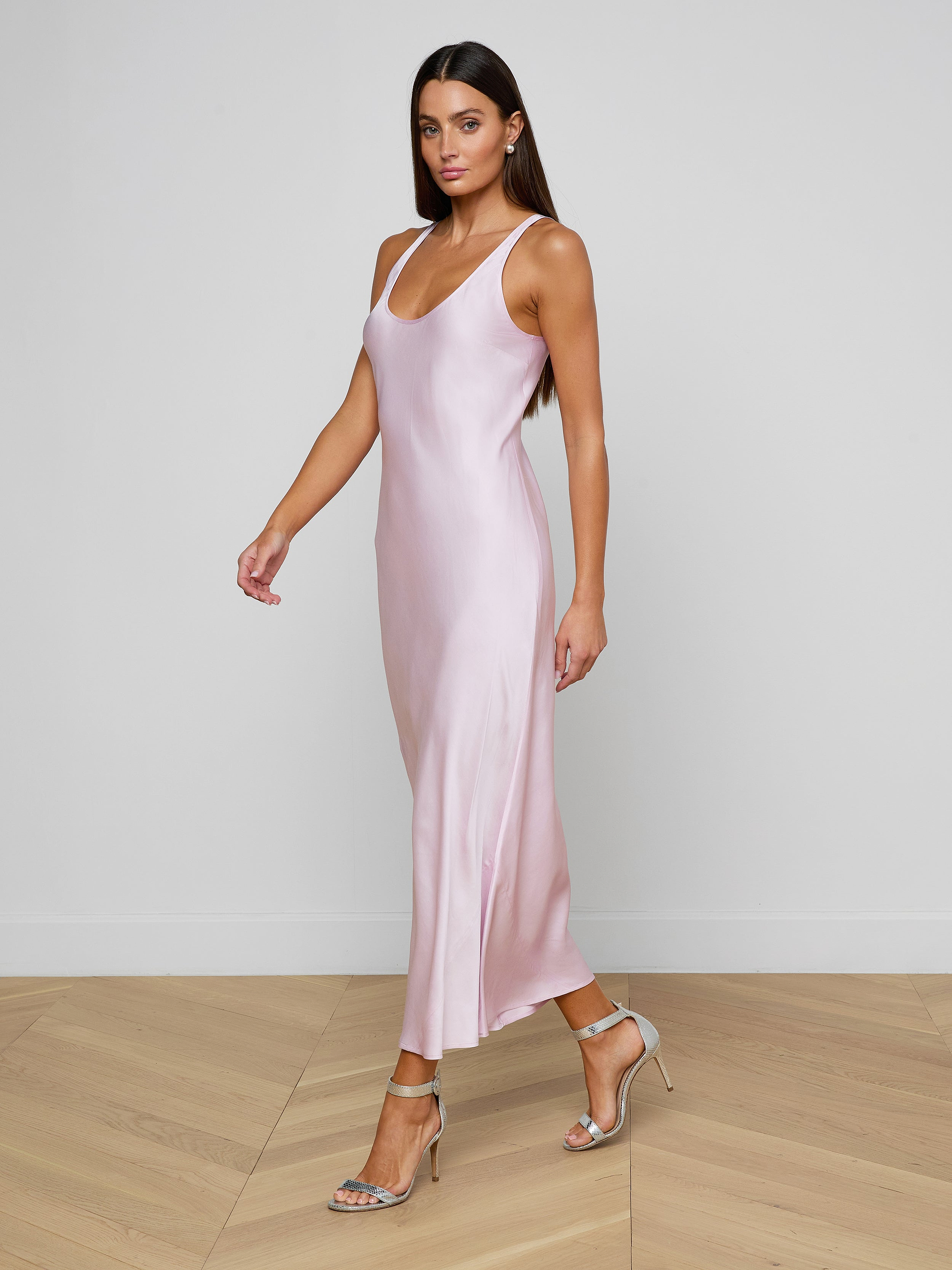 Wearing the Akiya Satin Maxi Dress in a sleeveless, pastel lilac design, a woman in strappy heels walks confidently against a plain, light background.