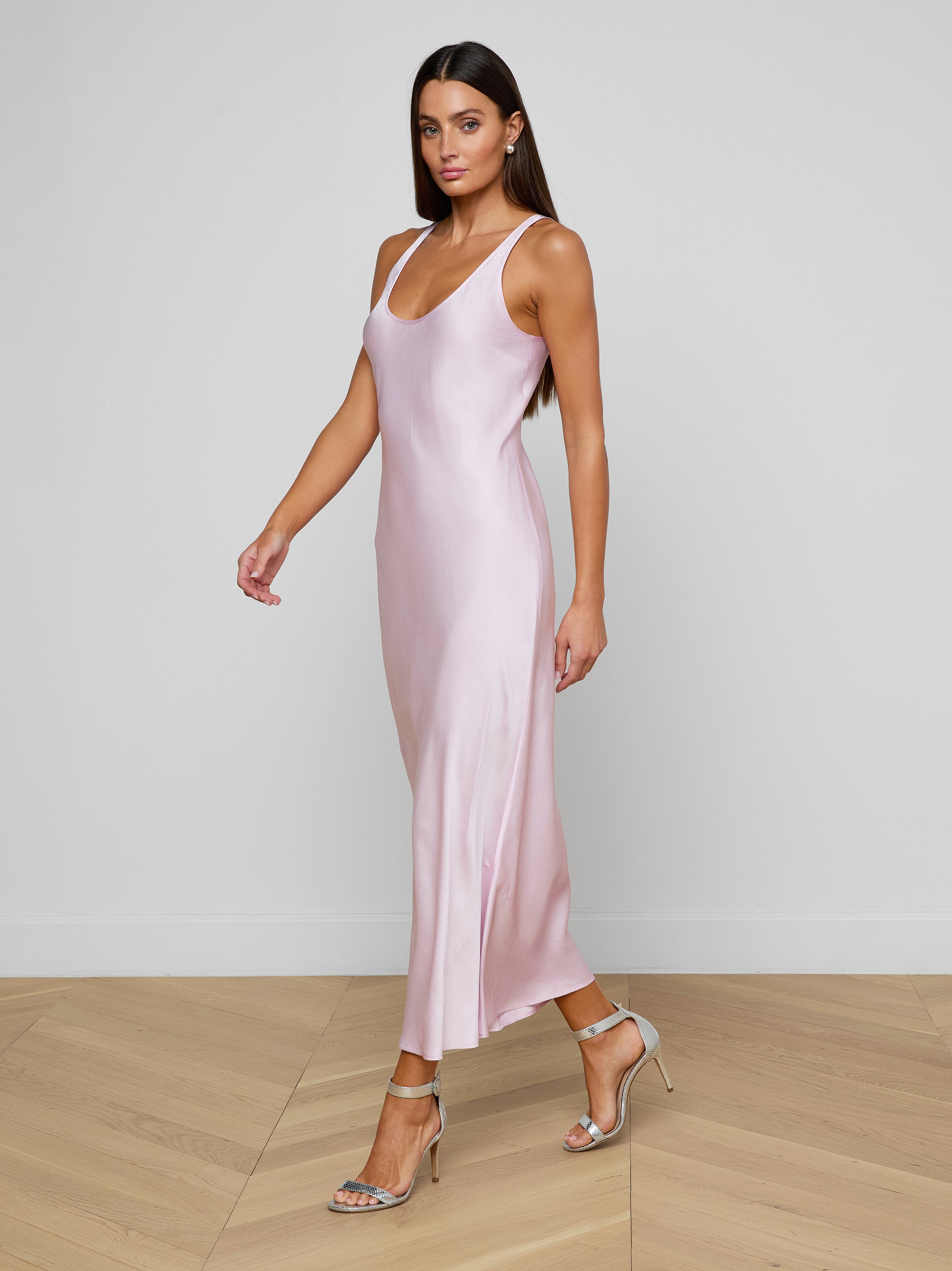 Wearing the Akiya Satin Maxi Dress in a sleeveless, pastel lilac design, a woman in strappy heels walks confidently against a plain, light background.
