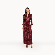 A woman stands against a plain white background wearing the Cameron Sequin Shirt Dress, a maxi-length, deep red sequin dress with long sleeves, paired with black strappy heels.