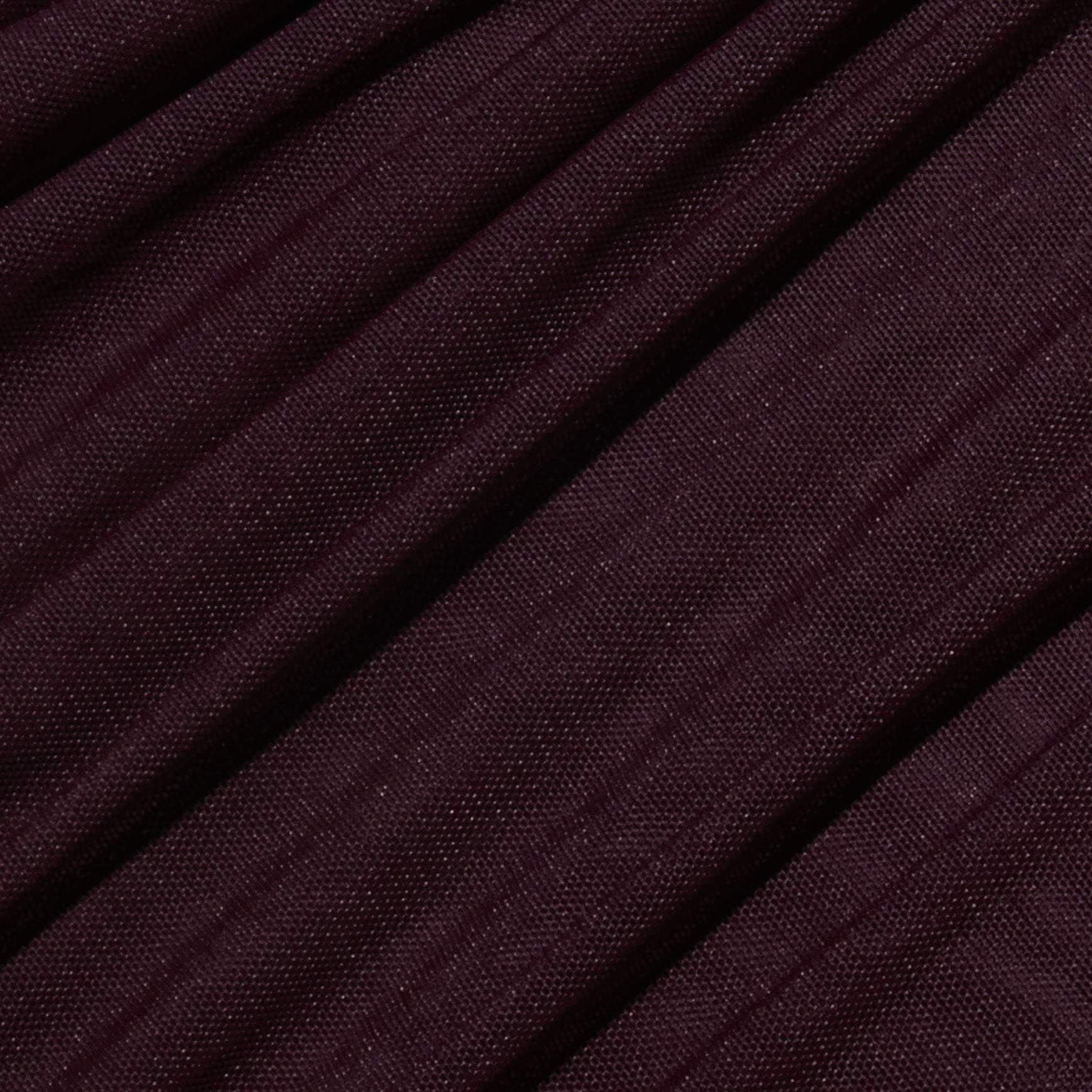 Close-up of ribbed maroon fabric with diagonal folds, highlighting the texture and weave of the Anya Shirred Dress in merlot red.