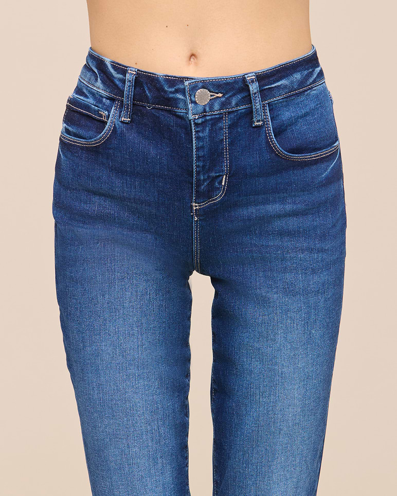 A person wearing high-waisted blue jeans, shown from the waist down against a plain background. The jeans have front pockets, belt loops, and visible stitching.