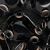 A close-up of black metal bicycle chain links with circular holes, showing the intricate and shiny mechanical parts in detail.