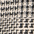 Close-up of black and white houndstooth fabric pattern, showing the classic geometric, jagged shapes repeated across the textile surface.