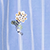 A small embroidered bee and white flower on light blue and white striped fabric.