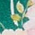 A close-up of a floral pattern featuring green, white, and yellow leaves with a hint of pink in the background.