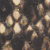 Close-up of a textured surface with a pattern resembling dark brown and tan reptile or snake scales, showing an overlapping arrangement with a glossy appearance.