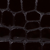 Close-up of a dark textured surface with a pattern resembling irregular hexagonal shapes, similar to reptile or alligator skin.