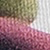 Close-up of textured, multicolored fabric with visible knit stitches in shades of green, white, and mauve.