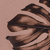 A close-up of a dark, stylized monstera leaf set against a muted pink background. The leafs cutouts and texture are highlighted, creating a modern, artistic look.