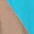Close-up of two pieces of fabric; one side is tan and the other is bright blue, meeting diagonally across the image. The fabrics appear slightly wrinkled.
