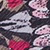 Close-up of a fabric with a colorful abstract pattern featuring pink, red, black, and gray shapes resembling leaves or petals overlapping each other.