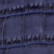 Close-up of a dark blue textured surface resembling crocodile or alligator skin, showing rectangular scales and ridged, raised patterns.