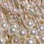 Close-up of several pearl-headed pins clustered together, with a shimmering gold or beige fabric background.