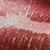 Close-up image of a pink and white textured surface, possibly showing a streak or brushstroke pattern with shimmering, reflective areas.