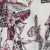A close-up of patterned fabric featuring intricate, abstract designs in black, red, and white. The motifs include geometric and organic shapes, creating a bold and artistic appearance.