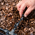Hand adjusting a black garden irrigation system on mulched ground | Vego Garden