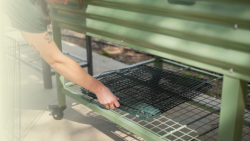 Folded wire cloche stored flat beneath a garden bench