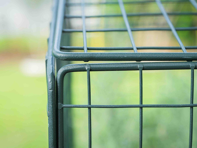 Wire cloche blending into a thriving raised-bed garden