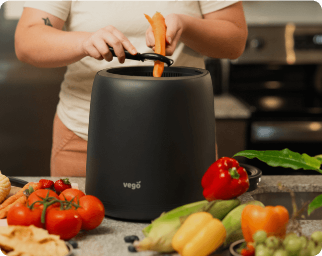 Person using a black Vego product with vegetables on a kitchen counter