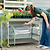 Gardener lifting a Pacific PC Cloche by its handle from a cream rolling raised garden bed| Vego Garden
