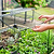 Hands aligning the removable lid and fastening clips on a Vego Garden wire cloche.| Vego Garden