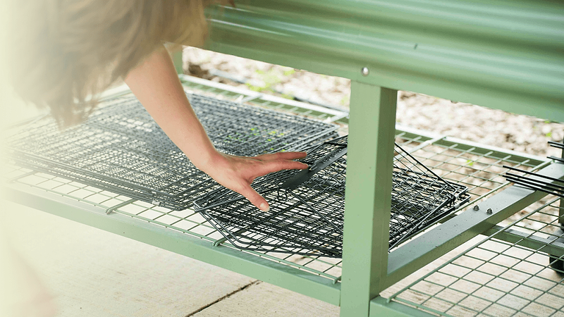 Vego Garden modular wire cloche folded flat beneath a potting bench for compact garden storage